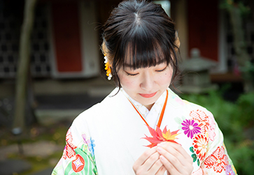 画像：白い振袖を着て紅葉を持つ女性