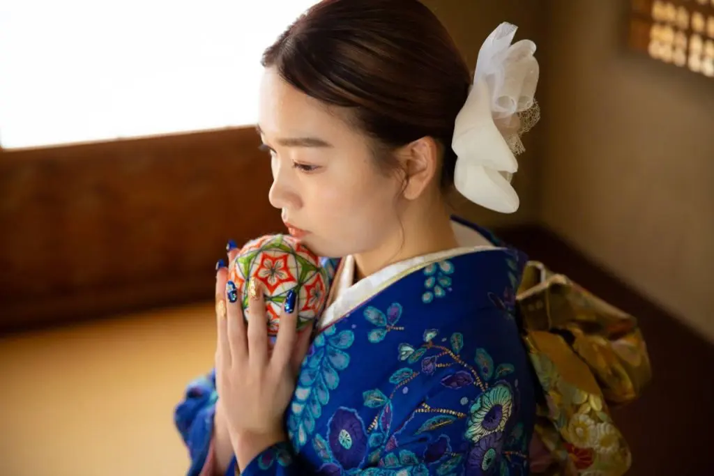 青色の振袖姿で鞠を持った女性