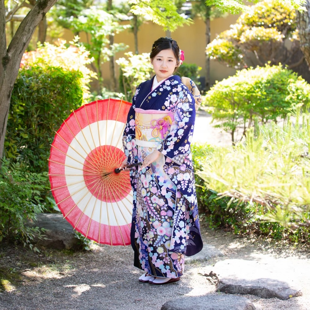 紺の辻が花の振袖を着て傘を持っている女性