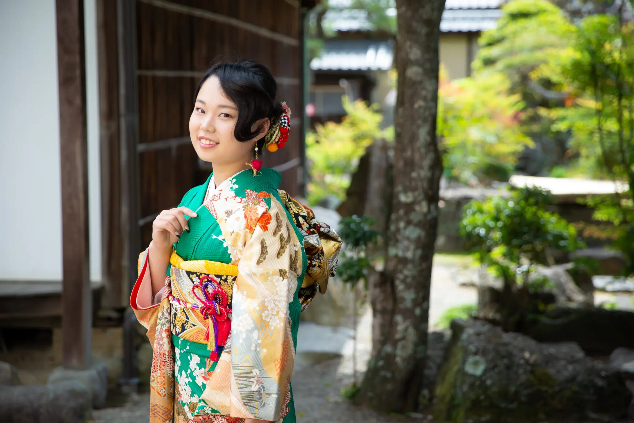 緑の振袖を着た笑顔の若い女性。