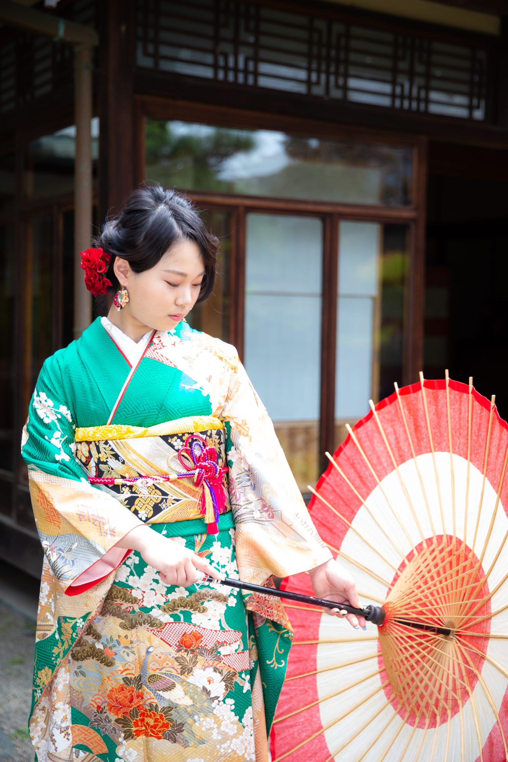 緑の振袖を着て和傘を持つ若い女性。