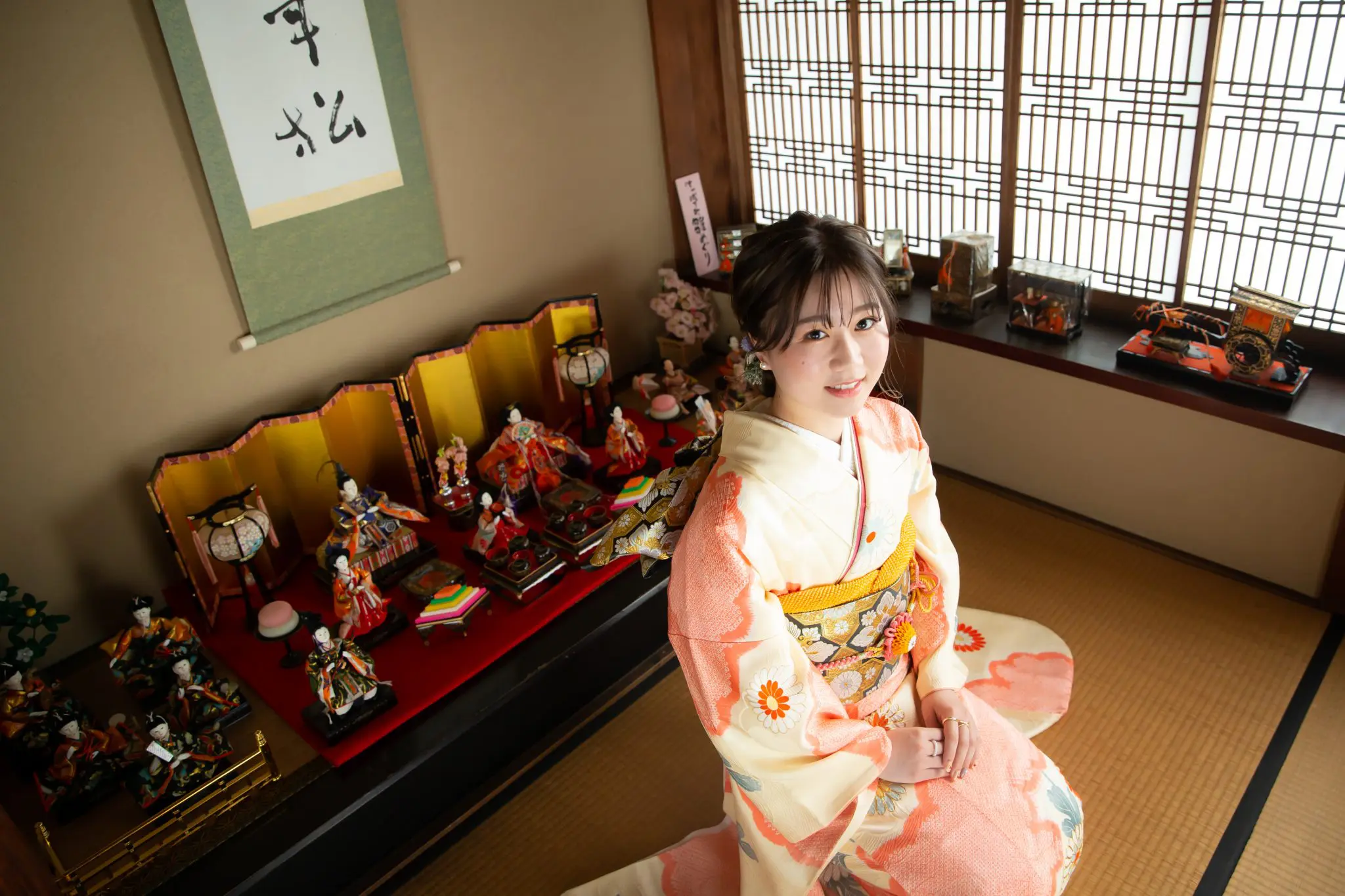 雛飾りの前に座る振袖姿の女性