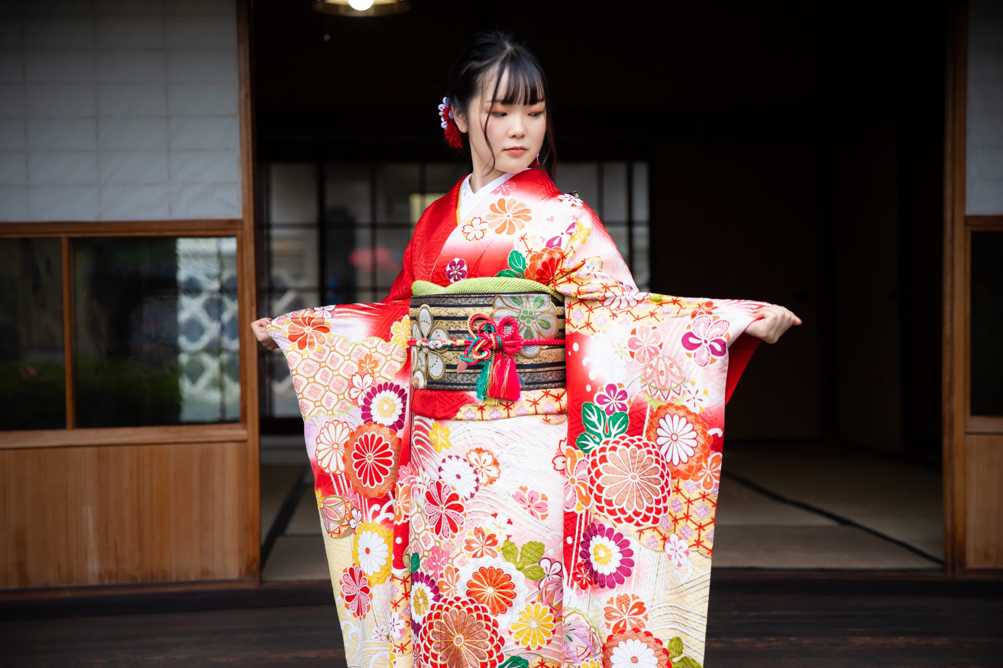 赤い振袖を着て袖を広げる女性