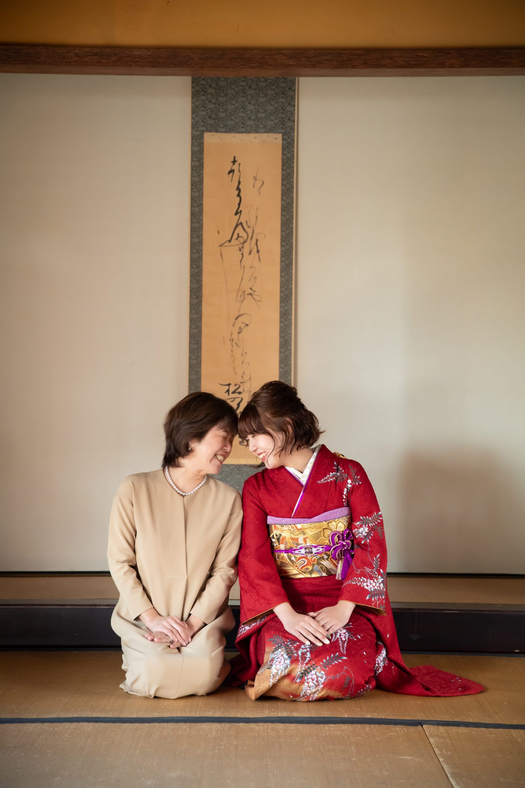 和室にならんで座る母親と赤い振袖を着た娘