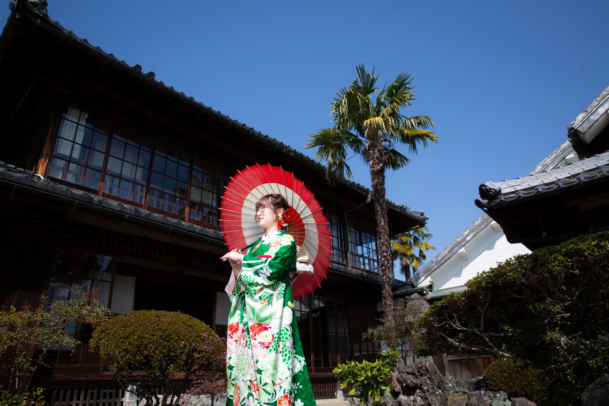和傘をさす緑の振袖姿の女性