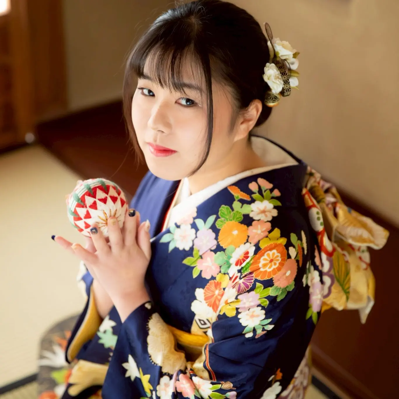 青い振袖を着て鞠を持った女性