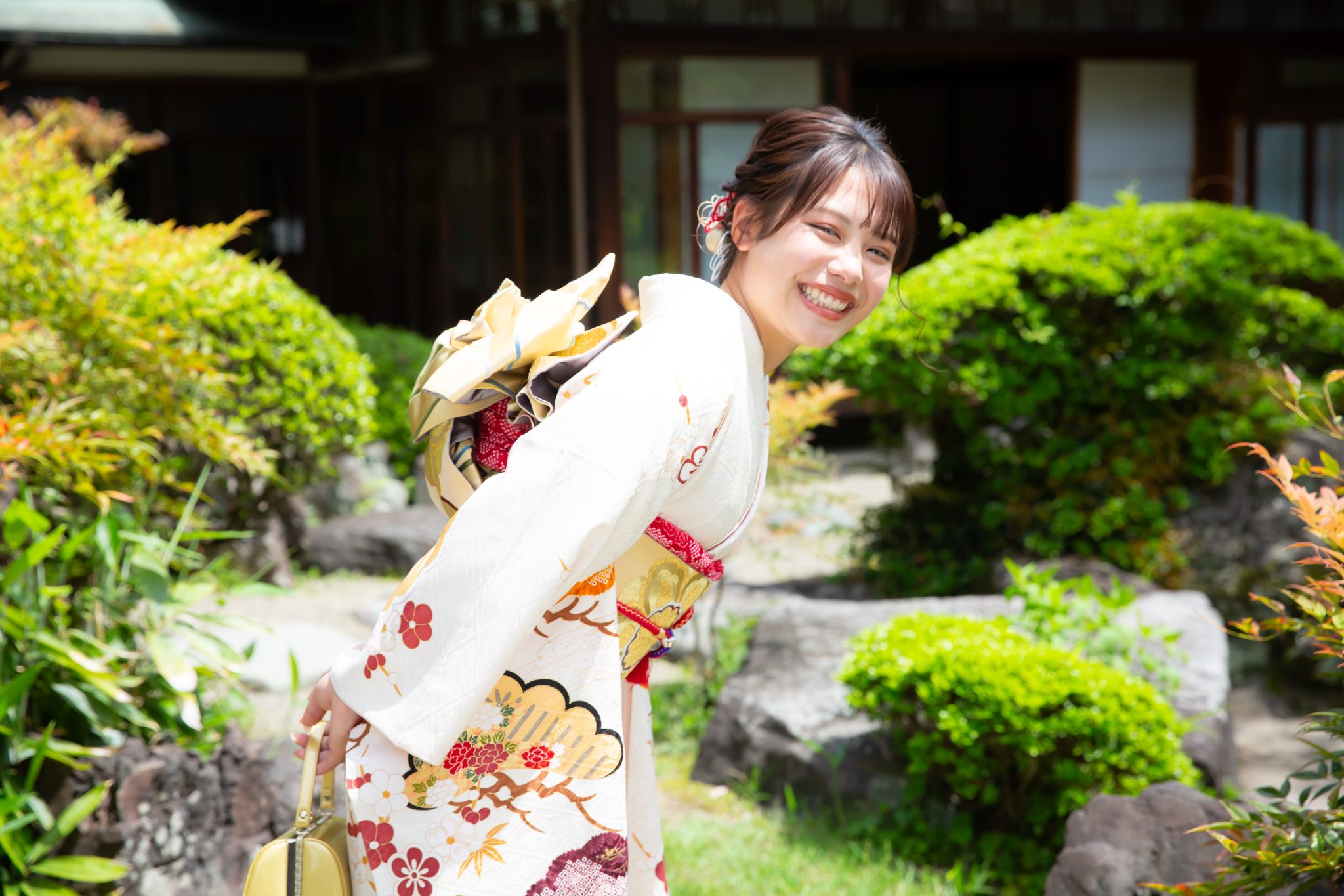 日本庭園にて、白の振袖姿でこちらに振り向く女性