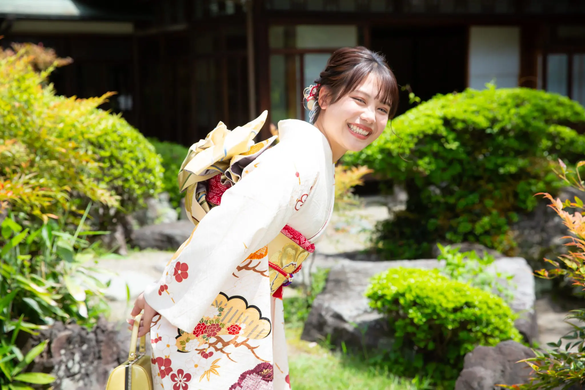 日本庭園にて、白の振袖姿でこちらに振り向く女性
