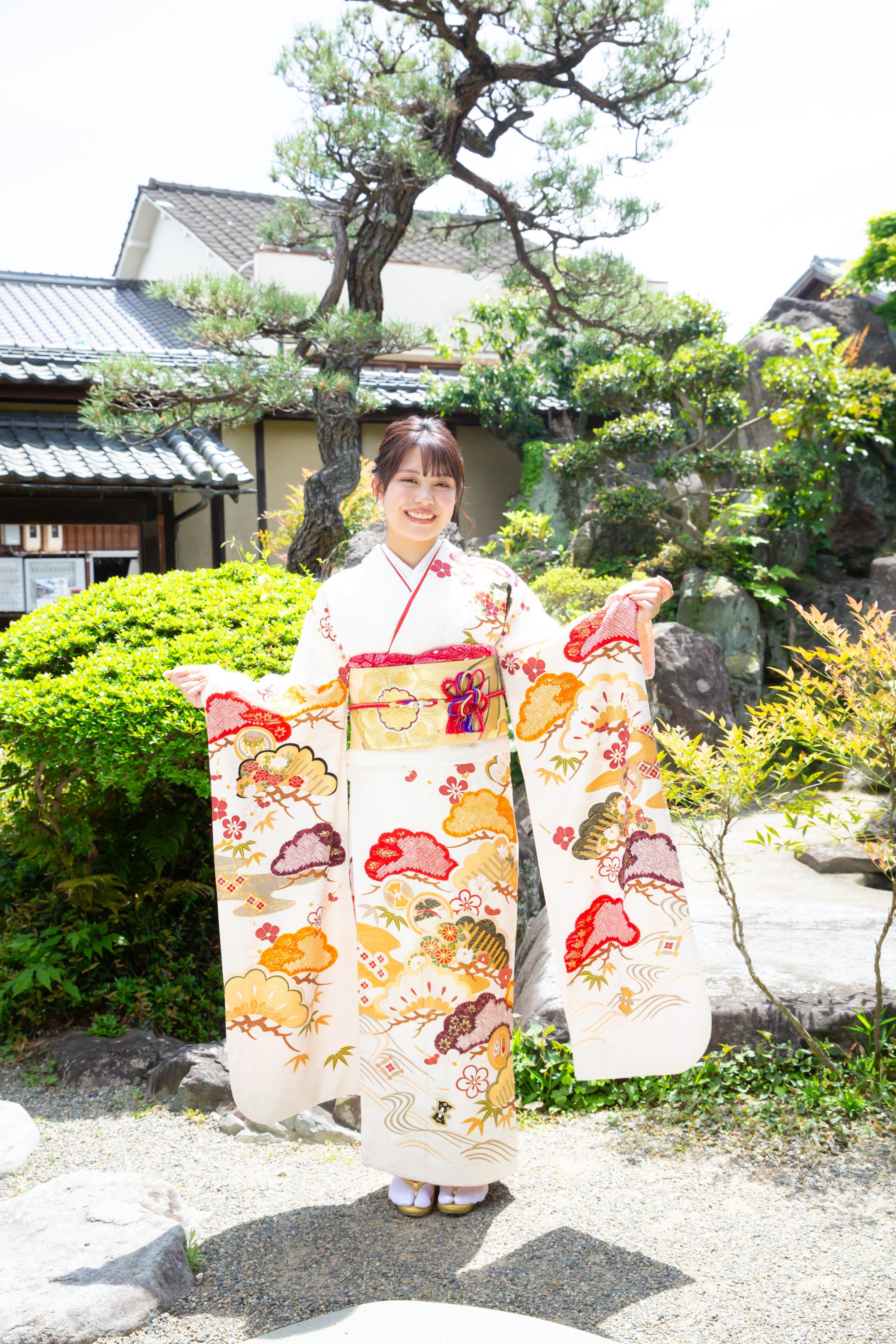 日本庭園で振袖の袖を広げる女性