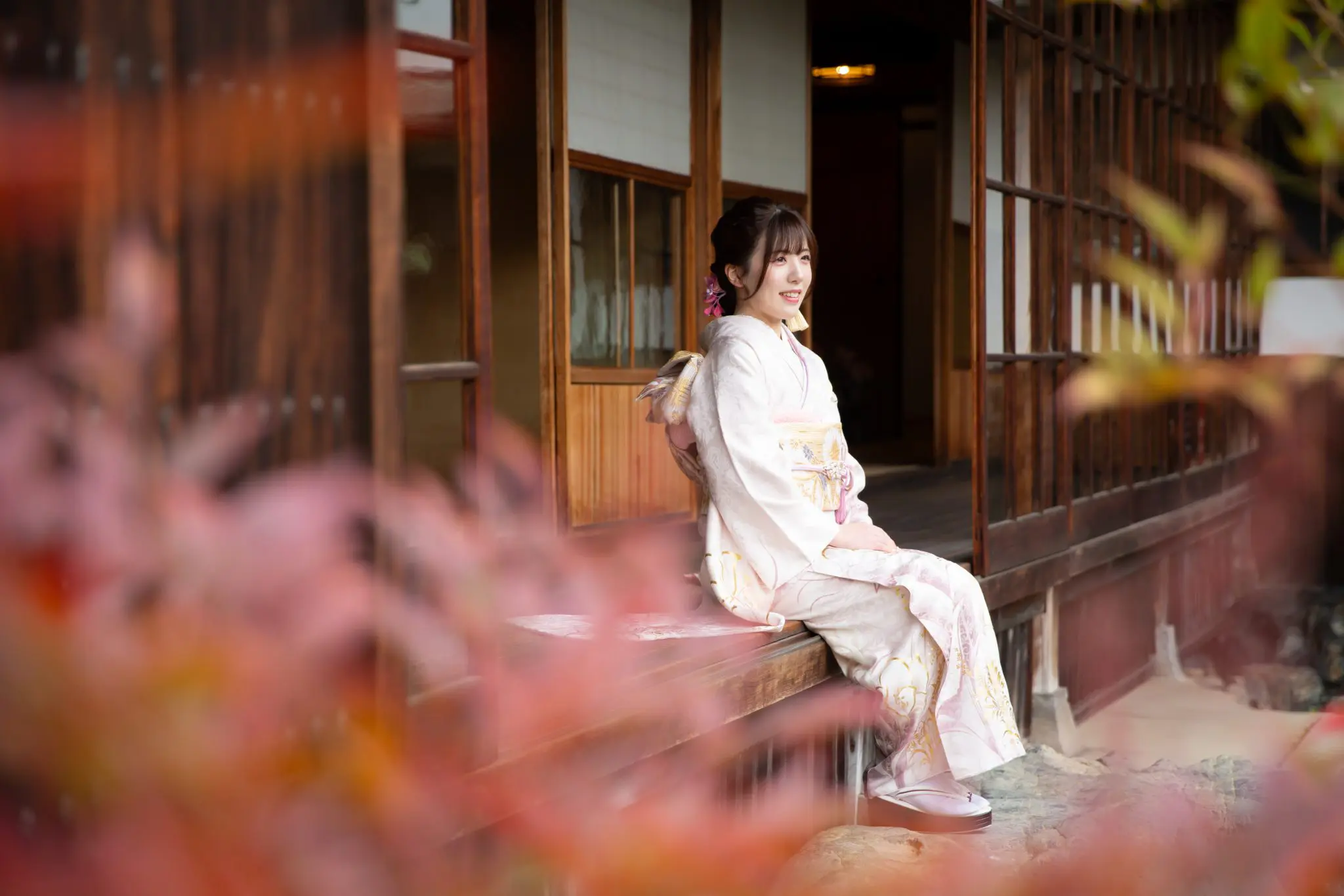 縁側に座る淡いピンク色の振袖の女性
