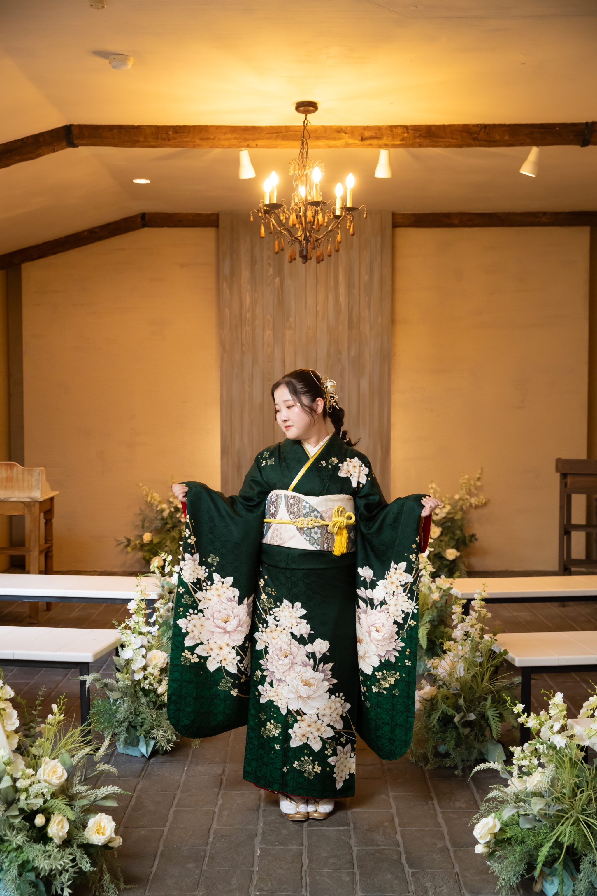 緑の振袖の袖を広げて立つ女性
