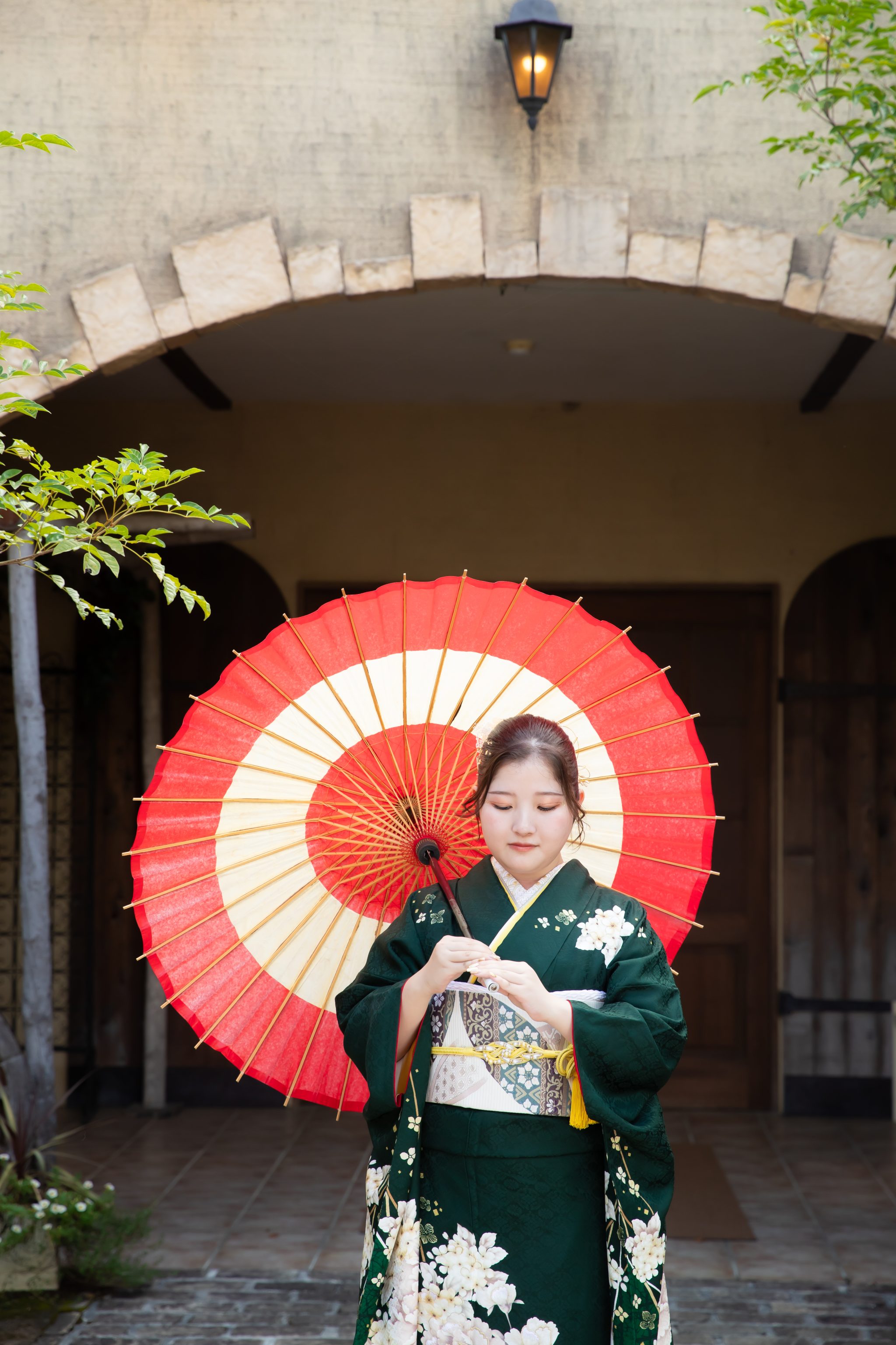 和傘をさして佇む緑の振袖を着た女性