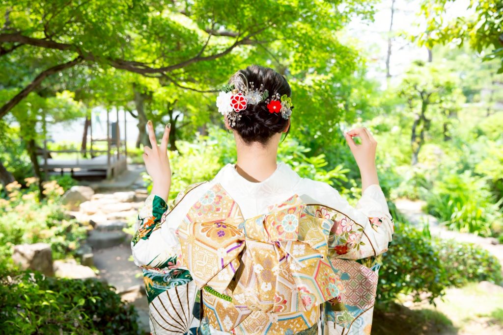 白い振袖を着て二十歳ポーズをした女性の後ろ姿