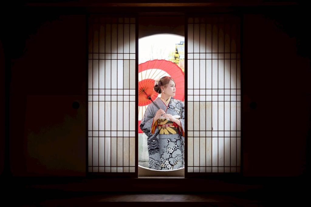 黒い振袖を着て和傘を差した女性