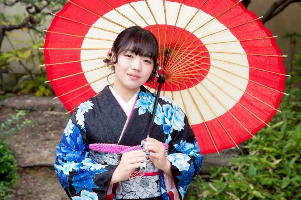 黒い振袖を着て傘を差した女性