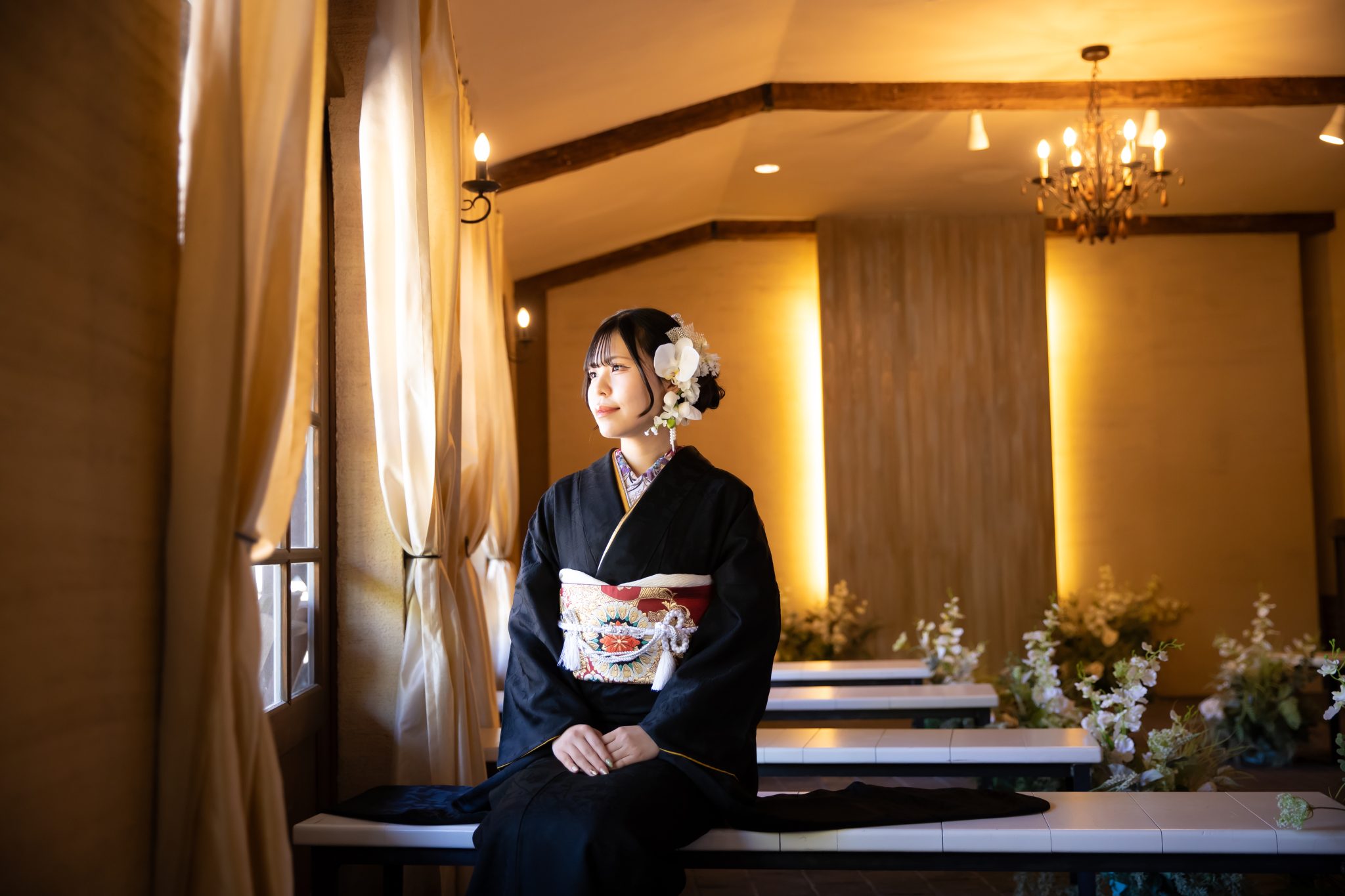 窓辺に座る黒い振袖を着た女性