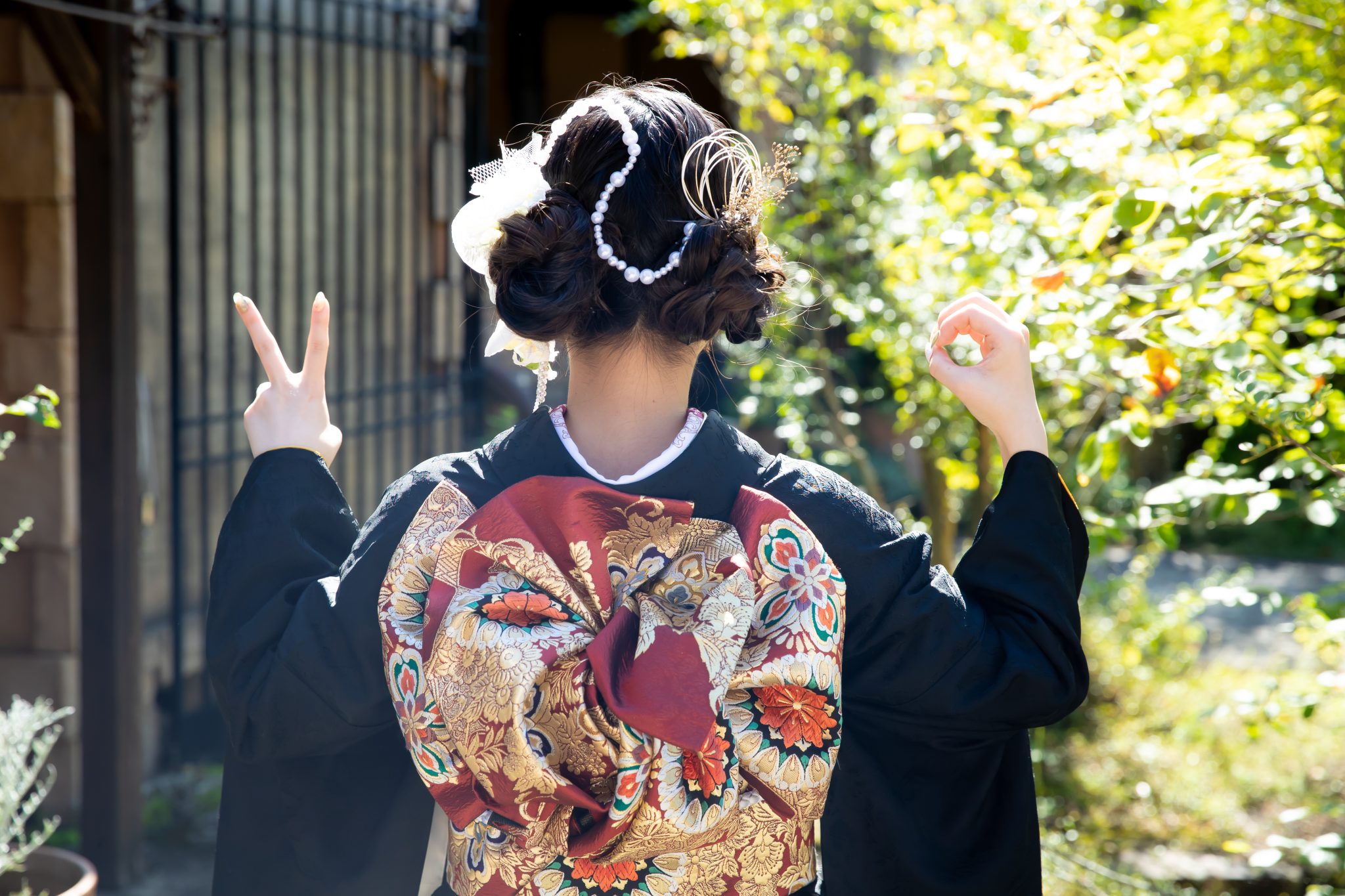 二十歳ポーズをする黒の振袖を着た女性の後ろ姿