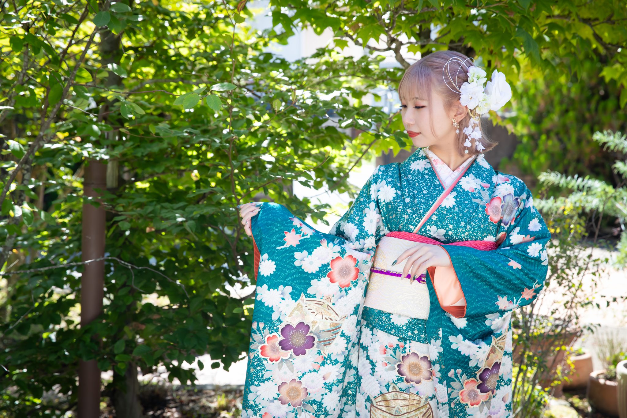 青緑色の振袖を着て袖を広げる女性